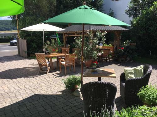 eine Terrasse mit Tischen und Stühlen und einem grünen Sonnenschirm in der Unterkunft Tektona "Bed & Breakfast" in Nidda