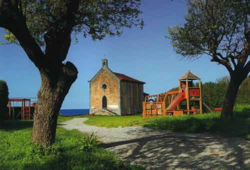 an old church and a playground next to a building at Bungalows Portuondo parking gratuito in Mundaka