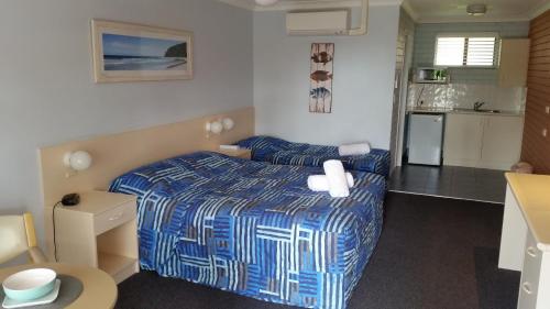 a small bedroom with a bed and a kitchen at Dolphins of Mollymook Motel in Mollymook