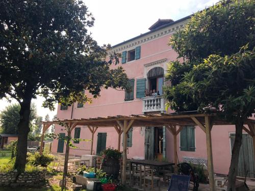 ein rosafarbenes Haus mit Leuten auf einem Balkon in der Unterkunft Pecore Ribelli in Mira