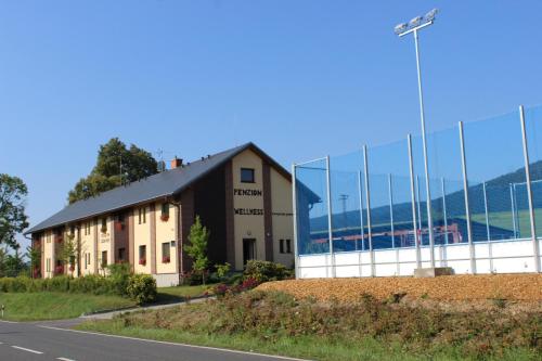 a building on the side of a road next to a fence at Penzion Ječmínek in Červená Voda