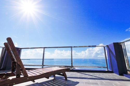 a wooden bench sitting on a balcony looking at the ocean at Two Home Inn in Hualien City