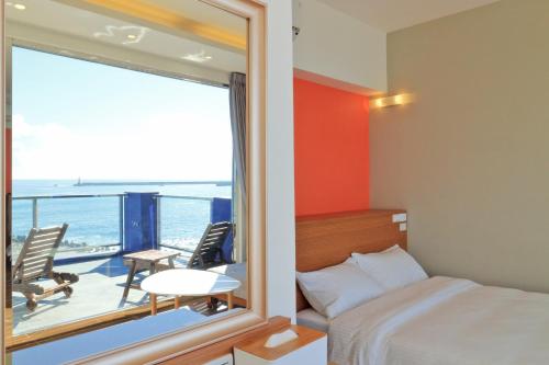 a bedroom with a bed and a balcony with a view at Two Home Inn in Hualien City