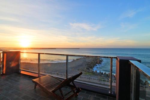 a balcony with a bench and the ocean at sunset at Two Home Inn in Hualien City
