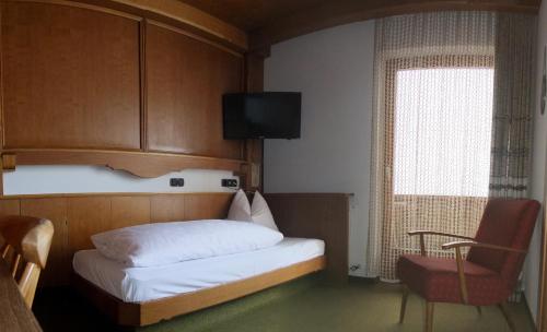 a small bedroom with a bed and a window at Hotel Garni Obermair in Mayrhofen