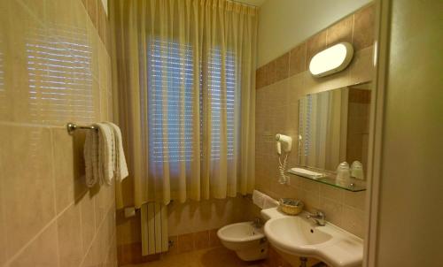 a bathroom with a sink and a toilet and a mirror at Albergo Le Sorgenti in Chianciano Terme