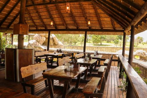 un restaurante con mesas y bancos de madera y techo en Knysna Elephant Park Lodge en Plettenberg Bay