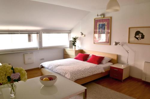 um quarto com uma cama com almofadas vermelhas e uma mesa em Studio in Ljubljana Center em Ljubljana