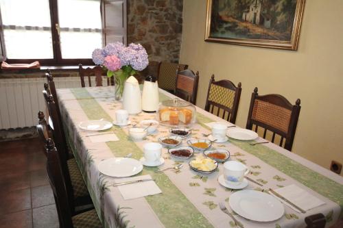 a table with plates and a vase of flowers on it at La Llosa in Villaviciosa