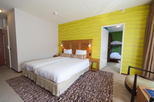 a bedroom with a large bed and a yellow wall at Fletcher Hotel Restaurant Sallandse Heuvelrug in Rijssen
