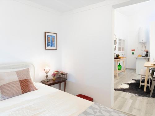 a white bedroom with a bed and a dining room at Lisbon Alfama Street View in Lisbon