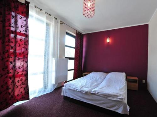 a bedroom with a bed and a purple wall at Hotel Arkadia in Ciechanowiec