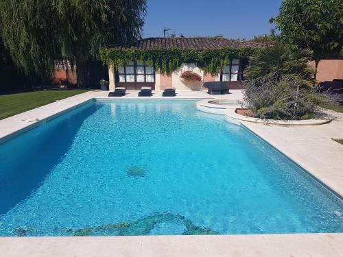 une piscine avec de l'eau bleue devant une maison dans l'établissement Appartement de charme en Provence, à Châteaurenard