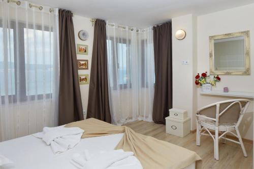 a bedroom with a bed and a chair and windows at Villa Elea in Nesebar