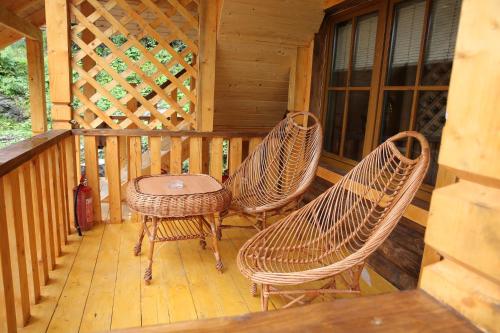 three wicker chairs and a table on the porch of a cabin at Zarinok in Pilipets