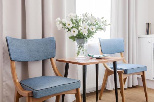 two chairs and a table with a vase of flowers at Apple Inn in Warsaw