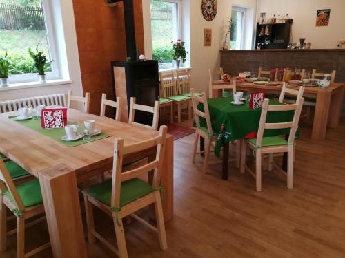 a dining room with wooden tables and green chairs at Penzion U Klujů in Věstín