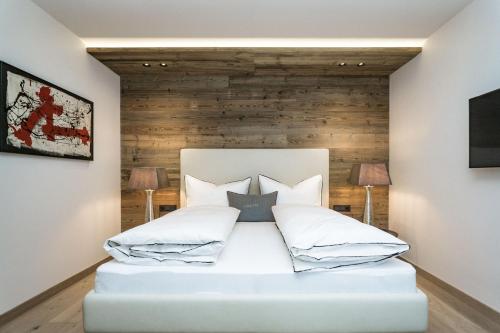 a bedroom with a white bed with a wooden wall at Appartements Erwin Hüttl III in Neukirchen am Großvenediger