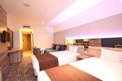 a hotel room with two beds and a couch at Quintessa Hotel Sapporo in Sapporo