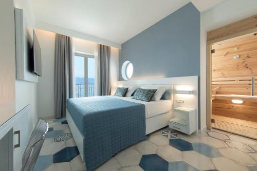 a hotel room with a bed, chair and a mirror at Lloyd's Baia Hotel in Vietri sul Mare