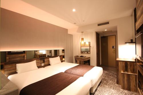 a hotel room with a large bed and a television at Quintessa Hotel Sapporo in Sapporo