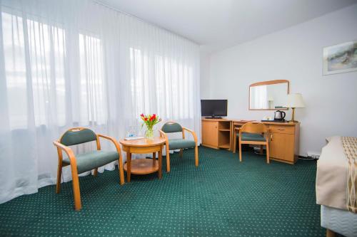 a hotel room with a table and chairs and a desk at Hotel Festival in Opole