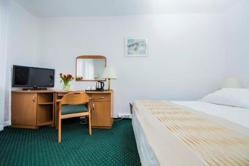 a hotel room with a bed and a desk with a television at Hotel Festival in Opole