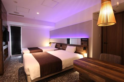 a hotel room with two beds and a desk at Quintessa Hotel Sapporo in Sapporo
