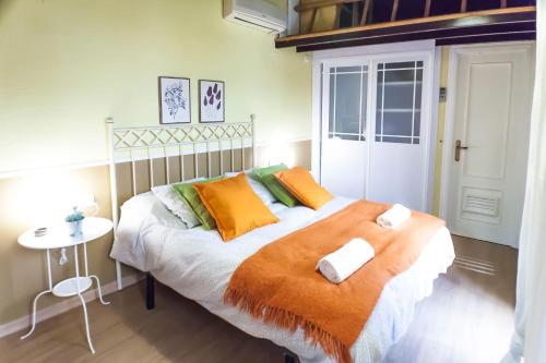 セビリアにあるCorral de la O Triana Apartmentのベッドルーム1室(オレンジと緑の枕が付いたベッド1台付)