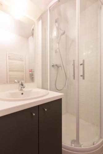une salle de bain blanche avec un lavabo et une douche dans l'établissement Vacanceole - Résidence Andromede, à Les Deux Alpes