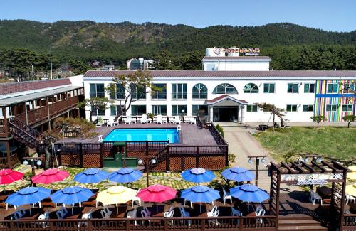 a hotel with a pool and tables with umbrellas at Hotel Mallipo in Taean