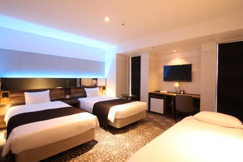 a hotel room with two beds and a television at Quintessa Hotel Sapporo in Sapporo