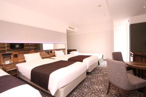 a hotel room with two beds and a table and chairs at Quintessa Hotel Sapporo in Sapporo