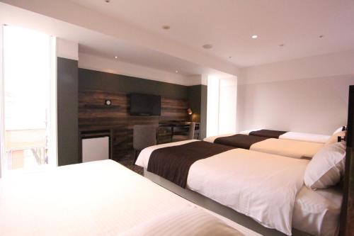 a hotel room with three beds and a television at Quintessa Hotel Sapporo in Sapporo