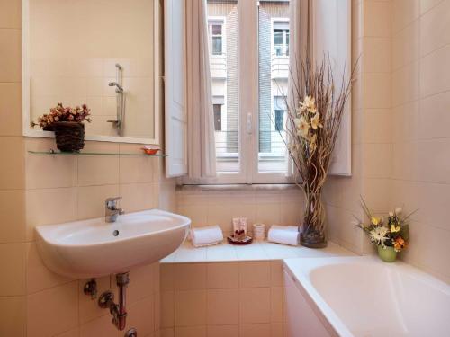 uma casa de banho com um lavatório, uma banheira e uma janela em Residenza Domiziano em Roma