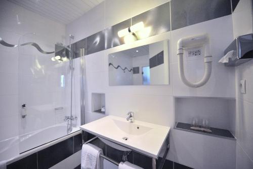 La salle de bains blanche est pourvue d'un lavabo et d'une douche. dans l'établissement Hôtel Continental Pau Centre, à Pau