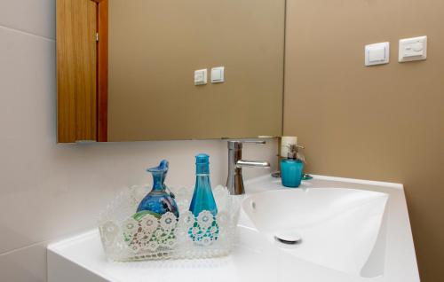 a bathroom sink with two blue glass bottles on it at Corcyra Nigra Apartment in Blato