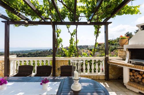 a patio with a table and chairs and a pergola at Villa Ariadne in Stalos