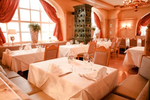 a restaurant with tables and chairs with white tablecloths at Schlosshotel Grünwald in Grünwald