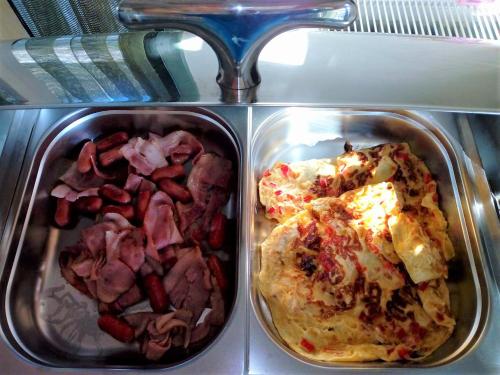 two trays of food with meat and a pizza at Amfitriti Palazzo in Nafplio