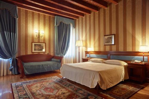 a bedroom with a bed and a chair in it at Villa Quaranta Tommasi Wine Hotel & SPA in Pescantina