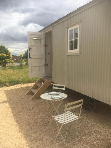 a patio with a table and chairs next to a building at Romantic secluded Shepherd Hut Hares Rest in Southwick