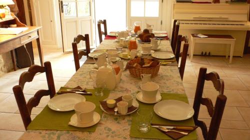 a dining room table with plates and dishes on it at La Héraudière Bed & Breakfast in Tours
