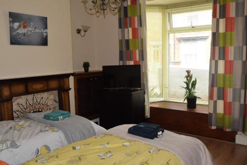 a bedroom with two beds and a television and a window at Kavig House in Lincoln