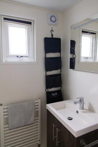 a bathroom with a sink and a mirror and towels at Olmenduin | Chalet 26 | Zeeland in Serooskerke