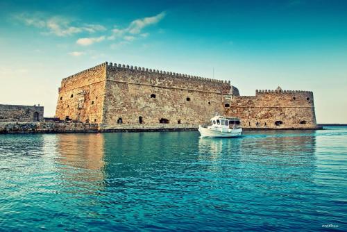 a boat in the water in front of a castle at Heraklion Youth Hostel in Heraklio