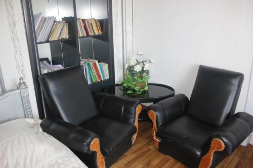 two black leather chairs and a table in a room at Guest house Gidi in Sighnaghi