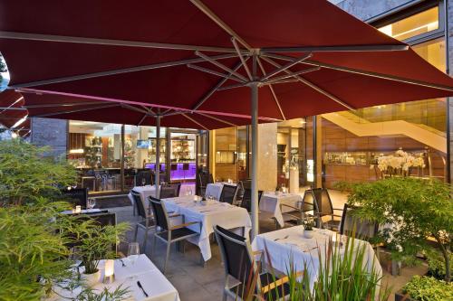 ein Restaurant mit Tischen, Stühlen und einem Sonnenschirm in der Unterkunft Meliá Düsseldorf in Düsseldorf
