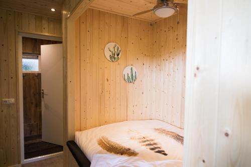 1 dormitorio con paredes de madera y 1 cama en una habitación en vakantiehuisje "ZUSJE", en Bruchterveld