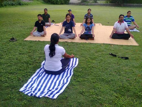 a group of people sitting on a blanket on the grass at The Meadows Resort and Spa in Aurangabad